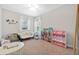 A bedroom with a white couch, carpeted floors, and lots of toys at 7721 Roma Dune Dr, Wesley Chapel, FL 33545