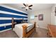 Comfortable bedroom featuring a wooden bed frame, blue-and-white striped accent wall, and neutral-colored carpet at 7721 Roma Dune Dr, Wesley Chapel, FL 33545