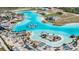 Bird's eye view of a community pool, complete with sandy beach, waterslides, and tropical landscaping at 7721 Roma Dune Dr, Wesley Chapel, FL 33545