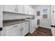 Well-organized laundry room with modern white cabinets, granite countertops, and new appliances at 7721 Roma Dune Dr, Wesley Chapel, FL 33545