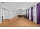 Bright and spacious living room featuring hardwood floors and decorative purple and white window treatments at 7721 Roma Dune Dr, Wesley Chapel, FL 33545