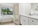 Bright bathroom with a large soaking tub, walk-in shower and white cabinets at 887 Lucas Ln, Oldsmar, FL 34677