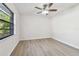 Bright bedroom with wood-look flooring, ceiling fan, and large window at 887 Lucas Ln, Oldsmar, FL 34677