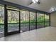 Enclosed screened porch featuring ceiling fan, tile floor, and view of the wooded backyard at 887 Lucas Ln, Oldsmar, FL 34677