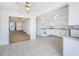 Eat-in kitchen features tile floors, and white appliances adjacent to the carpeted living room at 10022 Lily N St # N, Pinellas Park, FL 33782