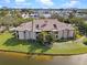 An aerial view of a condo building with well-maintained landscaping, situated on a pond and featuring a red door at 10263 Gandy N Blvd # 209, St Petersburg, FL 33702