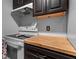 This kitchen shows a white oven, cook top, range hood and dark cabinetry with a wood countertop at 10263 Gandy N Blvd # 209, St Petersburg, FL 33702