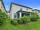 Landscaped backyard with tropical plants, lush green lawn, and a screened patio at 11008 Tahiti Isle Ln, Tampa, FL 33647