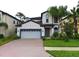 Two-story home with a gray garage door, well-maintained lawn, and vibrant landscaping at 11008 Tahiti Isle Ln, Tampa, FL 33647