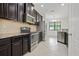 Well-equipped kitchen featuring stainless steel appliances, dark cabinetry, granite countertops, and tiled flooring at 11008 Tahiti Isle Ln, Tampa, FL 33647