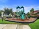 Community playground featuring slides, climbing structures, and a safety surface, surrounded by lush landscaping at 11008 Tahiti Isle Ln, Tampa, FL 33647