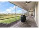 Covered brick patio offers a relaxing outdoor space with ceiling fans and views of the landscaped backyard and lake at 15315 Golden Beam Pl, Bradenton, FL 34211