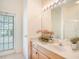 Updated bathroom with a white sink, wooden cabinet, large mirror, and exterior access at 1545 Deerbourne Dr, Wesley Chapel, FL 33543