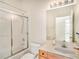 Bathroom featuring a tub with glass doors, a toilet, and a mirror over a single vanity at 1545 Deerbourne Dr, Wesley Chapel, FL 33543