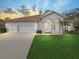 Inviting home exterior featuring a three-car garage, well-manicured lawn, and arched entryway with columns at 1545 Deerbourne Dr, Wesley Chapel, FL 33543