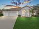 Inviting home exterior featuring a three-car garage, well-manicured lawn, and arched entryway with columns at 1545 Deerbourne Dr, Wesley Chapel, FL 33543