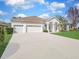 Well-maintained single-story home featuring a three-car garage, arched entry and green lawn at 1545 Deerbourne Dr, Wesley Chapel, FL 33543