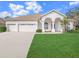 Well-maintained single-story home featuring a three-car garage, arched entry and green lawn at 1545 Deerbourne Dr, Wesley Chapel, FL 33543