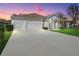 Inviting home exterior featuring a three-car garage, well-manicured lawn, and arched entryway with columns at 1545 Deerbourne Dr, Wesley Chapel, FL 33543