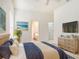 Main bedroom with blue accents, ensuite bathroom, television, and tropical artwork at 1545 Deerbourne Dr, Wesley Chapel, FL 33543