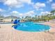 Large community swimming pool with brick deck, covered seating, and ample lounge chairs, ideal for relaxation at 1545 Deerbourne Dr, Wesley Chapel, FL 33543