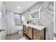 Beautiful bathroom featuring marble accent wall and a wood vanity with a white countertop and an illuminated mirror at 1811 Forest Dr, Oldsmar, FL 34677