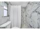 This bathroom has marble tile walls and flooring, a shower, and a modern toilet at 1811 Forest Dr, Oldsmar, FL 34677