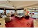 Cozy living room featuring plush red carpet, ample seating, and an abundance of natural light at 205 Seagull N Dr, Tarpon Springs, FL 34689