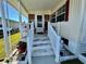 A welcoming front porch with white railings and steps leads to the entrance of this charming home at 205 Seagull N Dr, Tarpon Springs, FL 34689