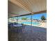 View of the community pool from under the covered patio with tables and chairs on the brick paver surface at 205 Seagull N Dr, Tarpon Springs, FL 34689