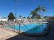 Community swimming pool enclosed by a white fence with lounge chairs and palm trees in the background at 205 Seagull N Dr, Tarpon Springs, FL 34689