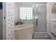 Cozy bathroom featuring a tub, glass block window and unique wallpaper at 315 Caloosa Palms Ct, Sun City Center, FL 33573