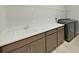 A well-equipped laundry room features a sink, counter space, cabinets, shelving, and a modern washer and dryer at 4375 Barletta Ct, Wesley Chapel, FL 33543