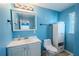 Blue bathroom featuring a sink, toilet, and white cabinet for storage at 6961 Dalkeith N Ave, St Petersburg, FL 33709