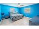 Bright blue bedroom featuring a ceiling fan and a grey bed with matching nightstand at 6961 Dalkeith N Ave, St Petersburg, FL 33709