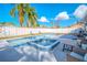 A shimmering pool and spa bordered with blue tile sit in a backyard featuring lounge chairs and a hanging chair at 6961 Dalkeith N Ave, St Petersburg, FL 33709