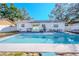 Backyard pool and spa area with outdoor seating, grill, and white exterior of home at 6961 Dalkeith N Ave, St Petersburg, FL 33709