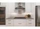 Modern kitchen with a stainless steel oven range hood, stone countertops, and white cabinetry at 7185 N Serenoa Dr, Sarasota, FL 34241