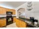 An efficient kitchen area featuring oak cabinets, granite countertops, and views into the living area at 7420 Bay Island S Dr # 281, South Pasadena, FL 33707