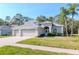 Inviting single-story home featuring a well-kept lawn, mature palm trees, and a three-car garage at 12545 Leatherleaf Dr, Tampa, FL 33626