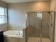 Bathroom features a glass shower and bathtub surrounded by beige tiles, a faucet, and a window at 13359 Orca Sound Dr, Riverview, FL 33579