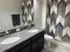 Shot of a bathroom with decorative shower curtain and black and granite double vanity at 13359 Orca Sound Dr, Riverview, FL 33579