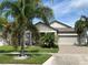 Beautiful home with a two-car garage, manicured lawn, stone accents, and swaying palm trees in a sunny, inviting setting at 13359 Orca Sound Dr, Riverview, FL 33579