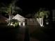 Exterior view of home at night with lovely landscaping, mature palms, and outdoor lighting at 13359 Orca Sound Dr, Riverview, FL 33579