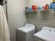 A laundry room featuring a wire shelf above a white top-load washing machine and a dryer at 13359 Orca Sound Dr, Riverview, FL 33579