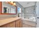 Bright bathroom featuring a soaking tub, wood cabinets, and a large mirror at 13507 Mango Bay Dr, Riverview, FL 33579