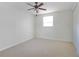 Clean bedroom features neutral carpeting, a ceiling fan, a window bringing in natural light, and closet space at 1401 Wickham Ln, Holiday, FL 34691