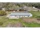 Aerial view of home with metal roof, and outdoor patio surrounded by a large grassy area and mature trees at 2040 Underwood Ln, Zephyrhills, FL 33540