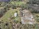 Aerial view of the expansive property with green space, sheds, a single Gathering home and bordering woods at 2040 Underwood Ln, Zephyrhills, FL 33540