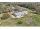Areal view shows home with metal roof, and outdoor patio surrounded by large grassy area and mature trees at 2040 Underwood Ln, Zephyrhills, FL 33540
